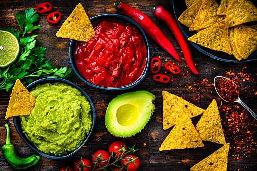 Salsa sauce, guacamole and nacho chips shot from above on dark wooden table. High resolution 42Mp studio digital capture taken with Sony A7rII and Sony FE 90mm f2.8 macro G OSS lens