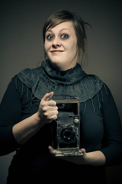 mime female photographer vintage female photographer posing with a mime like smile and big wide open eyes, holding an antique film camera ca04 stock pictures, royalty-free photos & images