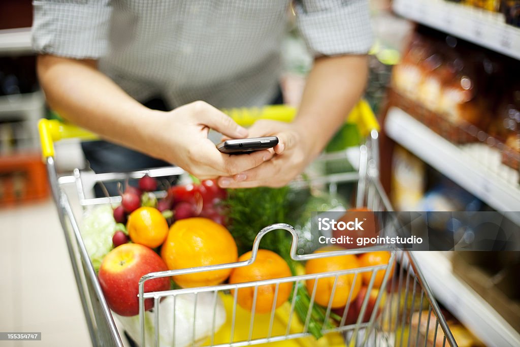 Человек SMS во время покупки - Стоковые фото Супермаркет роялти-фри