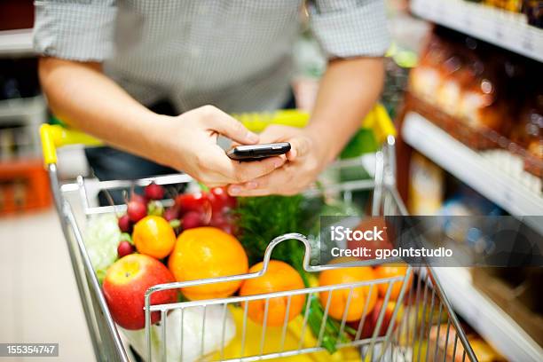 Человек Sms Во Время Покупки — стоковые фотографии и другие картинки Супермаркет - Супермаркет, Список покупок, Телефон