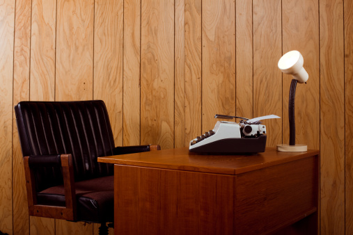 Horizontal image showing a retro 1970s office. Complete with a leather chair, typewriter and desk lamp.