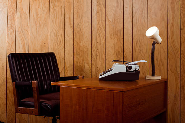 1970s office desk and chair Horizontal image showing a retro 1970s office. Complete with a leather chair, typewriter and desk lamp. wood paneling retro stock pictures, royalty-free photos & images