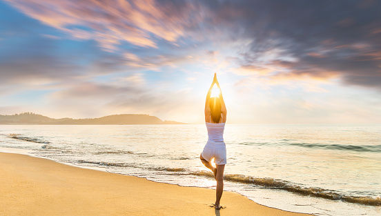 Woman practicing yoga at the beach