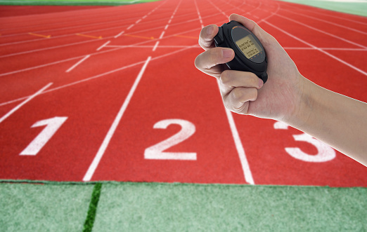 Human hand holding digital stopwatch on the running track