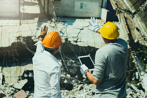 Demolition control supervisor and contractor discussing on demolish building.