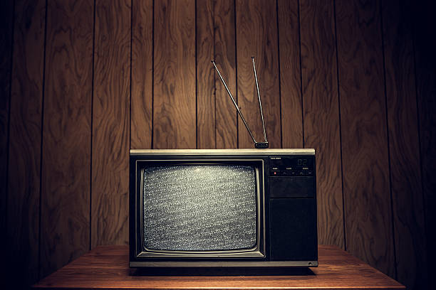 Retro Television in Wood Paneled Living Room Static plays on the screen of an old 1980's TV complete with signal antennae, sitting on a table in a domestic room with wood paneling on the walls.  Horizontal with copy space. television static photos stock pictures, royalty-free photos & images