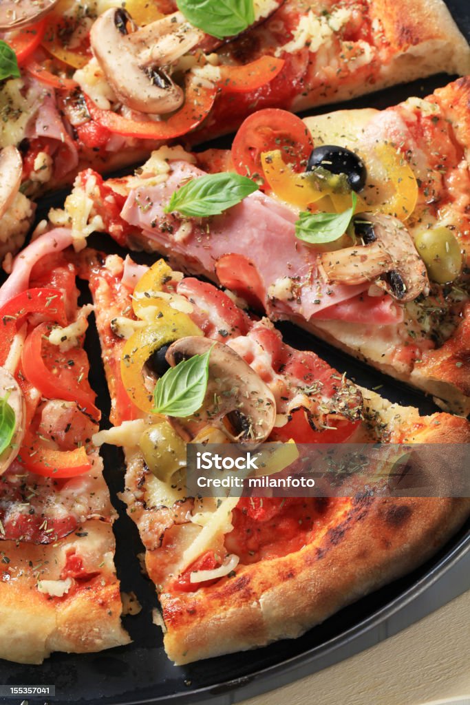 Ham pizza cut in pieces  Basil Stock Photo