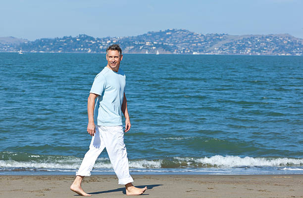 handsome mature man walking with ocean in background