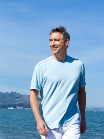 smiling mature adult at the seashore with ocean in background
