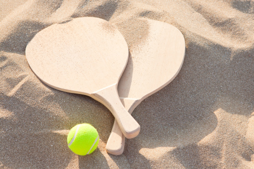 Beach tennis racquets and ball over sand. 