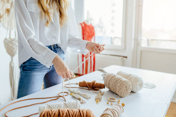 istock Creative hobby handmade macrame for home decoration. Close up of women's hands weaves macrame. Handmade macrame belt in work process. Female hobby. 1553571915
