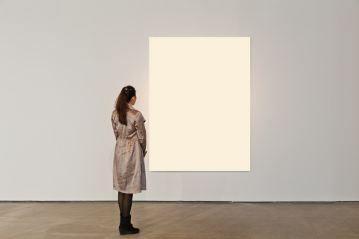 One woman looking at white frame in an art gallery