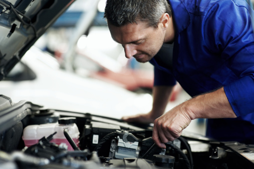 Closeup of an experienced mechanic servicing a car at his workshop - Copyspace