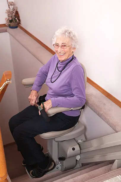 93 year old woman using stair lift in her home.
