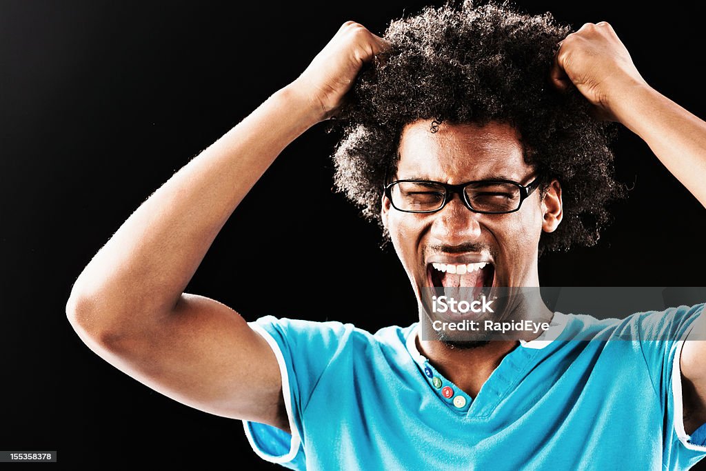 Furioso uomo giovane lacrime i suoi capelli contro nero - Foto stock royalty-free di Ebete