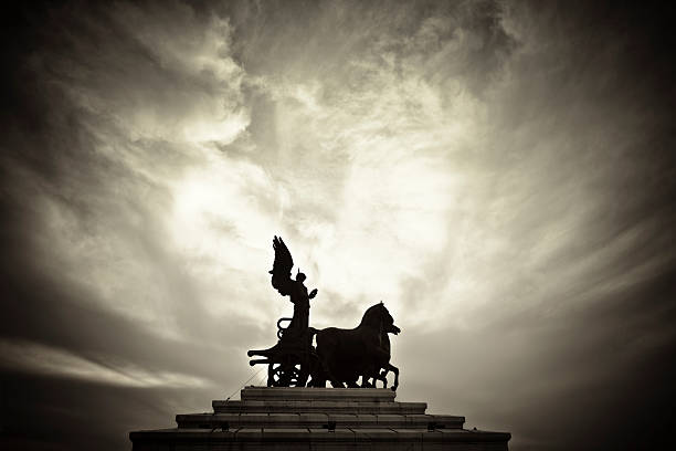 Goddess on a Chariot Silhouette against an evening sky of a goddess on a chariot statue, located atop the historic Monumento Nazionale a Vittorio Emanuele II (National Monument to Victor Emmanuel II) building in central Rome, Italy. chariot photos stock pictures, royalty-free photos & images