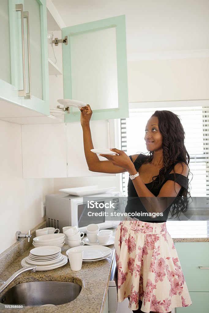 Organizing Kitchen Young adult black woman organizing in kitchen. Adult Stock Photo