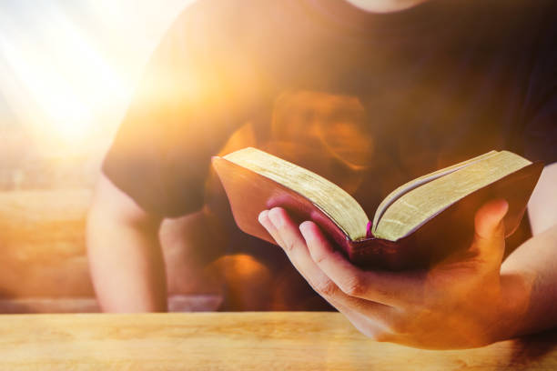 istock a man hand holding the holy bible on wooden table 1553588081