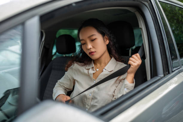 istock Young Woman Putting on Seat Belt Before Driving 1553590374