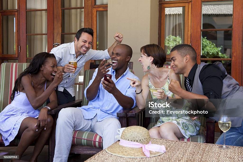 Friends Cheering At Receiving Good News Over Their Mobile Phone  30-39 Years Stock Photo