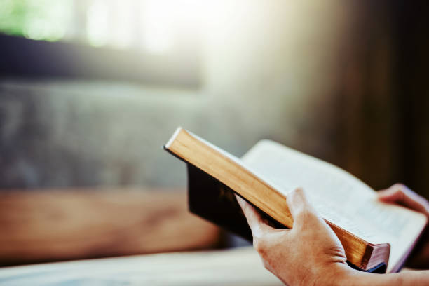 istock a human hands hold  while reading th open holy bible on wooden table 1553591594