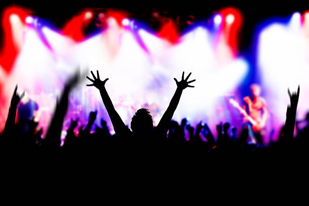 Concert Excitement Fans raising hands in excitement at a rock concert, some blur and noise because of low light and fast movement mosh pit stock pictures, royalty-free photos & images