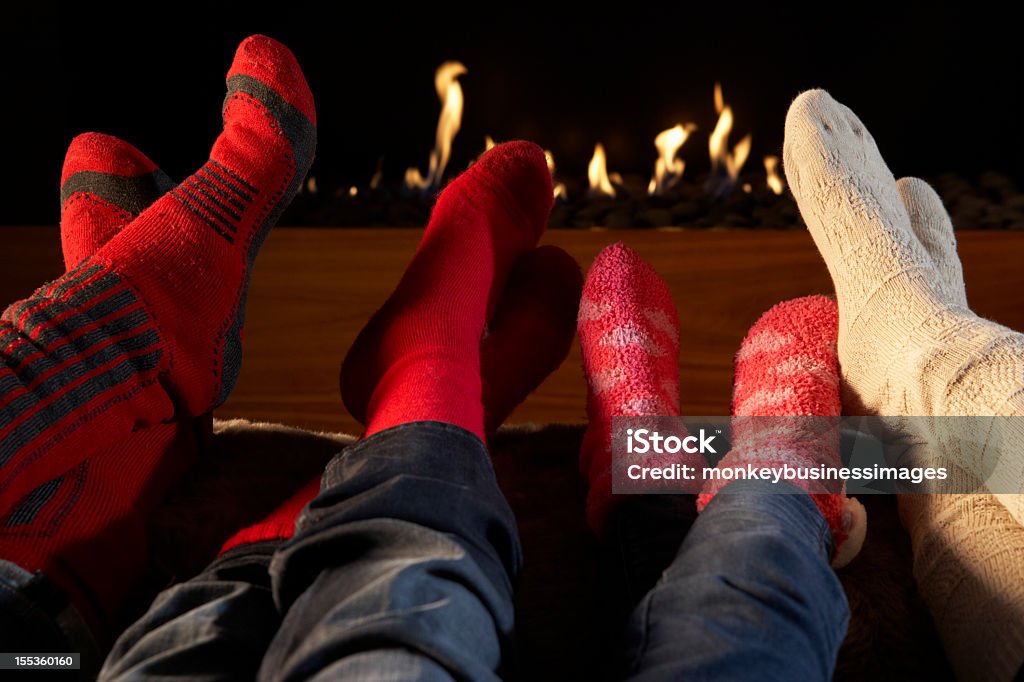 Quatre paires de pieds dans des chaussettes réchauffement par cheminée - Photo de Famille libre de droits