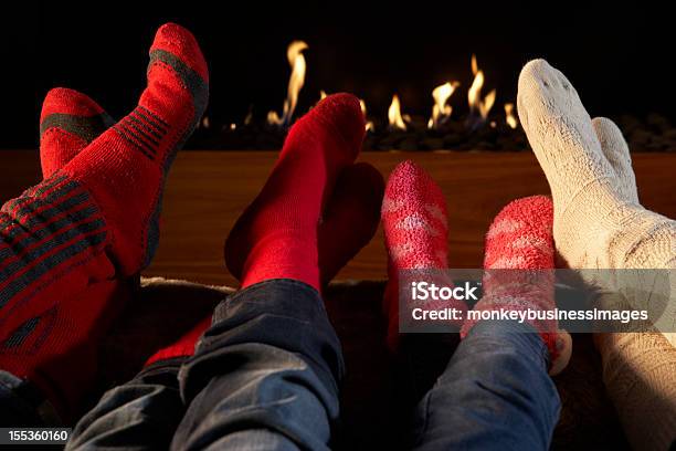 Photo libre de droit de Quatre Paires De Pieds Dans Des Chaussettes Réchauffement Par Cheminée banque d'images et plus d'images libres de droit de Famille