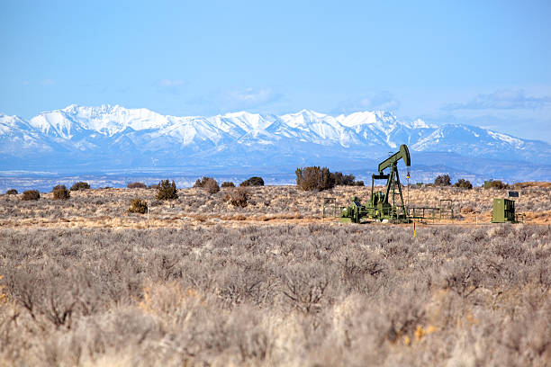 oil rig desert and snowcapped peaks stock photo