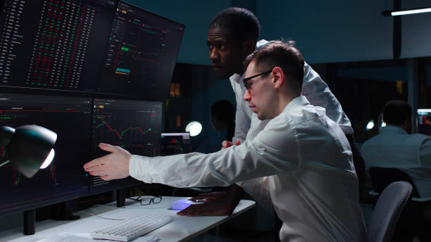 istock African-American and caucasian brokers analyze real-time stock market graphs on multiple monitors 1553604088