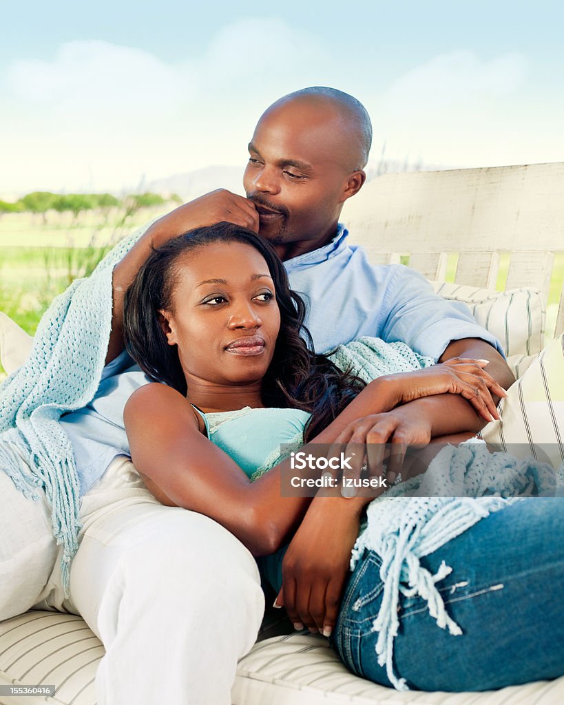 Happy couple Happy ethnic couple relaxing on seat outdoors. Blue Stock Photo