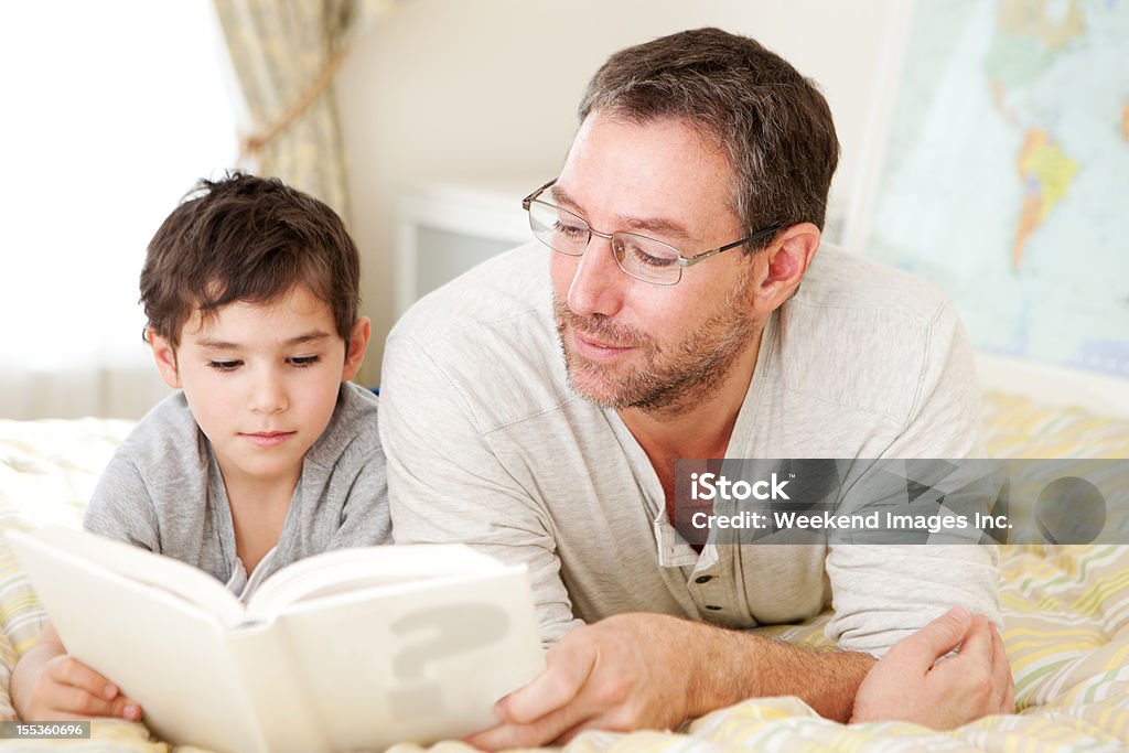 Padre leggendo un libro a Suo figlio - Foto stock royalty-free di Abbigliamento casual