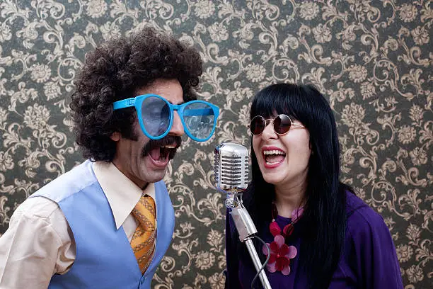 Photo of Two friends in seventies style singing on old fashioned microphone