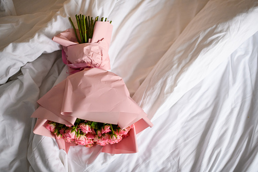 Overhead view of beautiful just delivered to hotel number bouquet of fresh pink roses in pink wrapping paper on white background