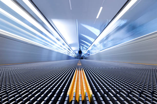 Person on a moving escalator with yellow stripes Man walks down the people mover in an airport; elevated walkway photos stock pictures, royalty-free photos & images