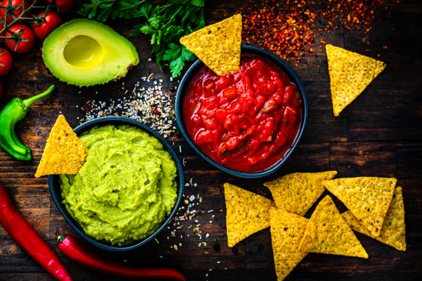 istock Mexican food: salsa sauce, guacamole and nacho chips shot from above on dark wooden table. 1553624212