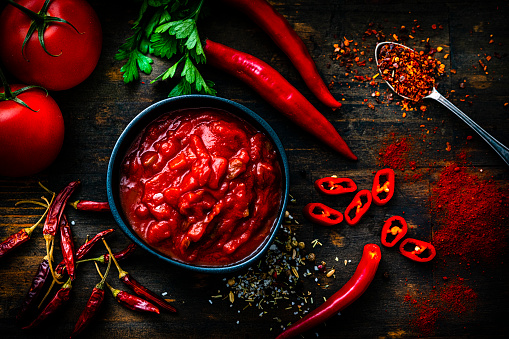 Red hot chili sauce with ingredients shot from above on dark wooden table. High resolution 42Mp studio digital capture taken with Sony A7rII and Sony FE 90mm f2.8 macro G OSS lens