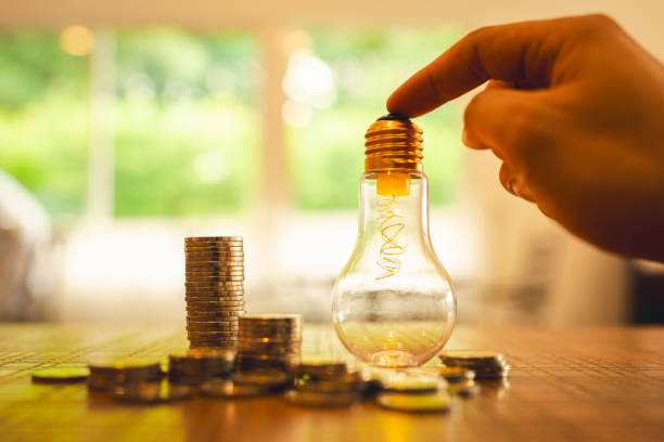 Hand holding a light bulb with coins stack. Money management, financial plan, business idea and Creative ideas for saving money concept. stock photo