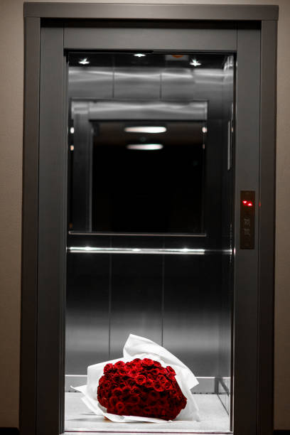 istock Large bouquet of red roses in white wrapping paper on elevator's floor 1553633847