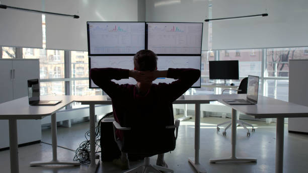 istock Back view of financial advisor work at multi-screen workstation and relax 1553643258
