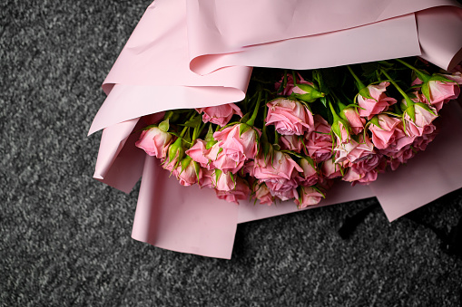 Overhead view of beautiful wedding bouquet of pink roses wrapped in pink paper on dark background
