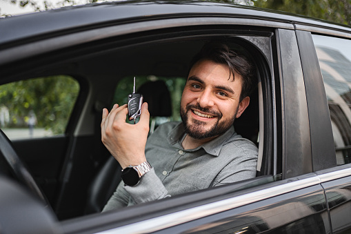 Portrait of smiling white businessman holding his car key in the car