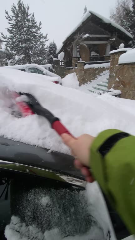 pov man cleaning car of snow after winter blizzard