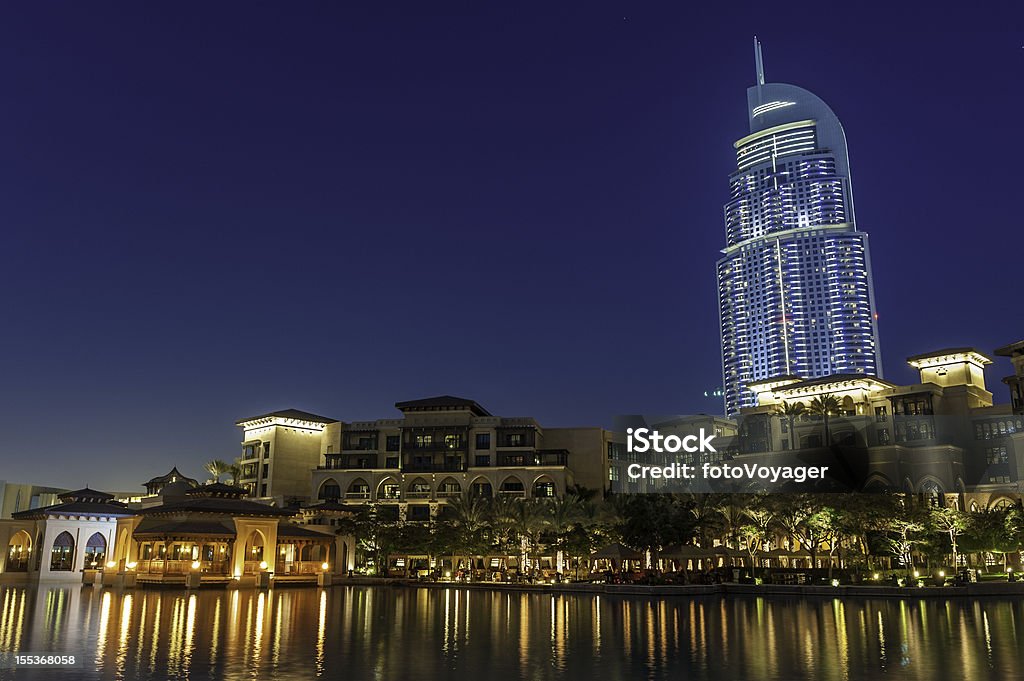 Dubai high rise hotel luxury apartments waterside restaurants at dusk Luxury high rise hotels, waterfront restaurants and exclusive housing developments reflecting in the still waters of the lake between the Dubai Mall and Burj Khalifa under deep blue dusk skies, United Arab Emirates. ProPhoto RGB profile for maximum color fidelity and gamut. Dubai Stock Photo