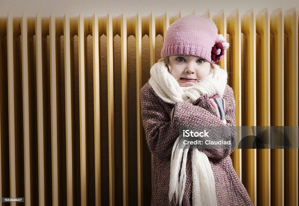 Chica en frente de radiador - Foto de stock de Frío libre de derechos