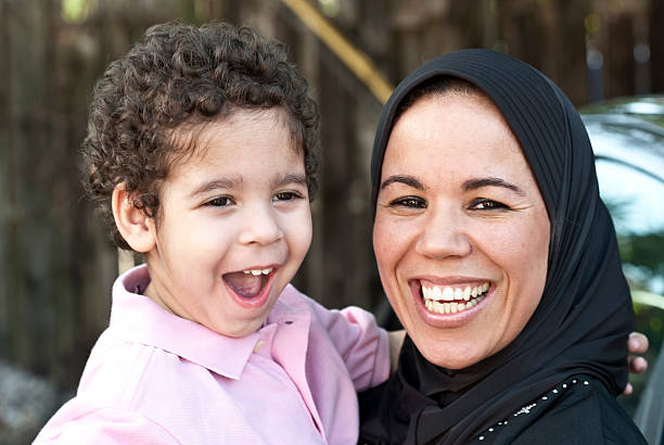 Smiling muslim woman posing with her son outdoors