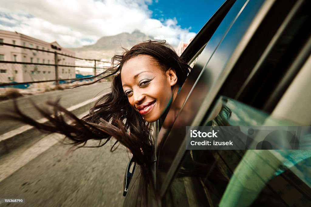Enjoying a car ride Beautiful african woman enjoying a car ride, leaning out of a car window and smiling at the camera. Car Stock Photo