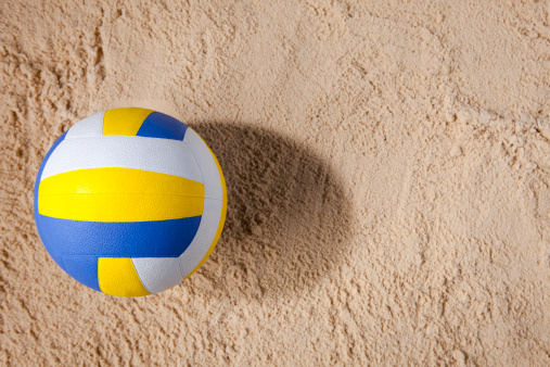 Beach volleyball sitting in the sand in the morning light