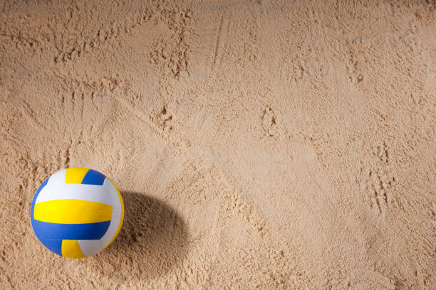 Beach volleyball sitting on the sand Studio shot of a beach volleyball sitting on the sand with masses of copy space. beach volleyball stock pictures, royalty-free photos & images