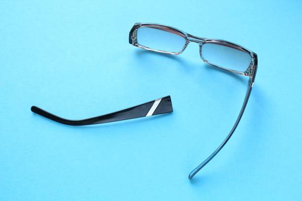 istock Old broken eyeglasses with damaged legs on blue background. Poor eyesight. Reuse and repair concept. Idea of health 1553692410